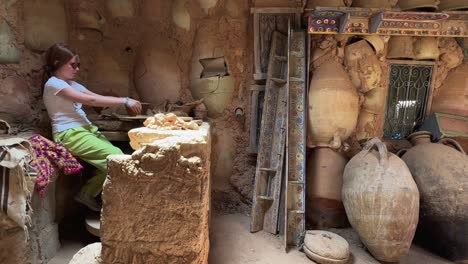 Little-tourist-girl-at-work-with-clay-in-rural-pottery-workshop-of-Tunisia