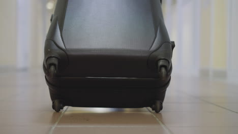 Small-wheels-of-big-black-suitcase-spin-on-tile-floor