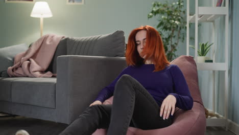 Woman-with-ginger-hair-comes-to-sit-on-bean-chair-after-work
