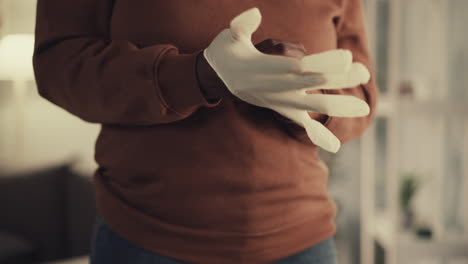 African-American-woman-puts-on-white-rubber-glove-at-home