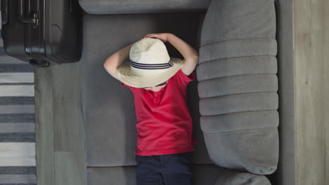 Stylish-small-boy-puts-hands-behind-head-lying-on-sofa