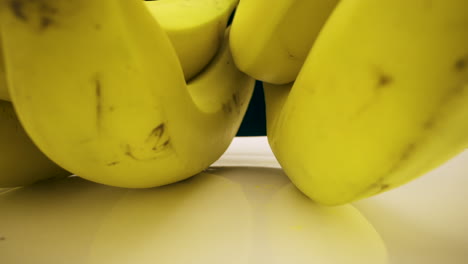 Bewegung-Entlang-Eines-Bündels-Köstlicher-Reifer-Bananen-Auf-Einem-Weißen-Teller