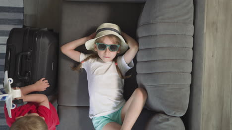 Toddler-plays-with-airplane-while-sister-rests-on-couch