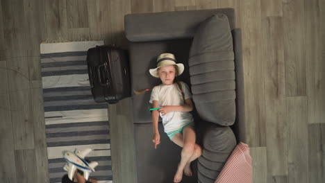 Little-girl-plays-with-sunglasses-lying-in-sofa-on-room