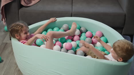 Joyful-children-have-fun-in-pool-with-balls-in-living-room