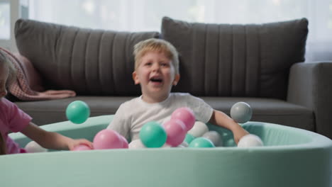 Laughing-little-children-jump-into-soft-ball-pool-at-home