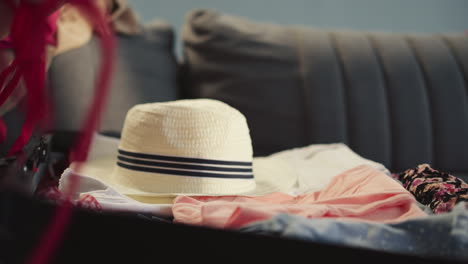 Girl-puts-hat-into-suitcase-mother-gathers-luggage-on-sofa