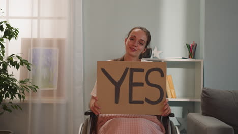 Positive-disabled-woman-smiles-holding-poster-with-word-Yes