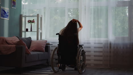 Behinderte-Frau-Berührt-Haare,-Die-Im-Rollstuhl-Am-Fenster-Sitzt