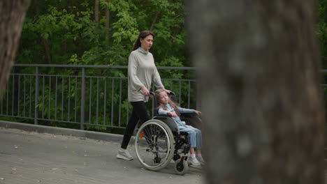 Mom-walks-on-pavement-with-daughter-sleeping-in-wheelchair