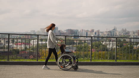 Mother-shows-city-panorama-to-little-daughter-in-wheelchair