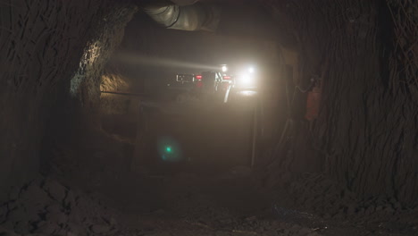 Heavy-mining-vehicle-with-big-dipper-drives-into-dark-mine