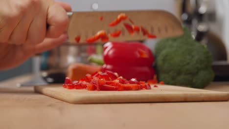 Housewife-cuts-fresh-red-pepper-on-wooden-board-with-knife