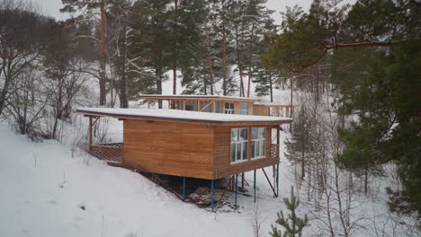 Small-wooden-house-with-big-windows-built-on-snowy-slope