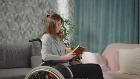 Junge-Frau-Mit-Behinderung-Sitzt-Im-Rollstuhl-Und-Liest-Ein-Buch