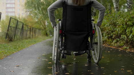 Woman-with-spinal-cord-injury-moving-along-asphalt-road