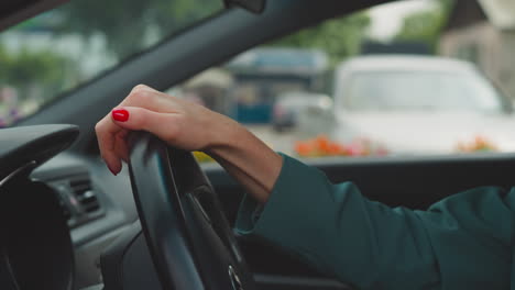 Hands-of-woman-with-red-nails-turning-steering-wheel-in-car
