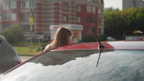 Junge-Fahrerin-Mit-Langen-Haaren-Steigt-In-Ein-Rotes-Auto