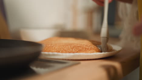 Frau-Buttert-Hausgemachten-Pfannkuchen-Mit-Einem-Weißen-Silikonpinsel