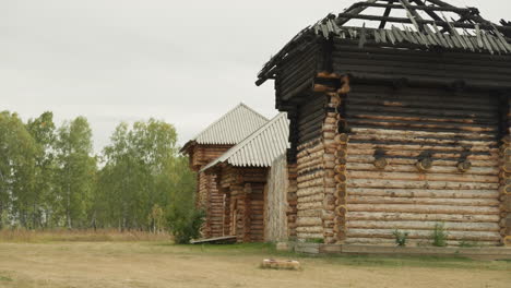 Old-log-house-with-burnt-by-fire-roof-on-cloudy-summer-day