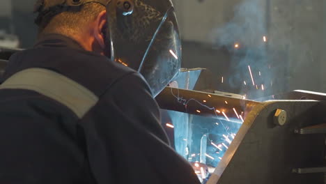 Male-labourer-with-safety-mask-welds-steel-carcass-at-plant