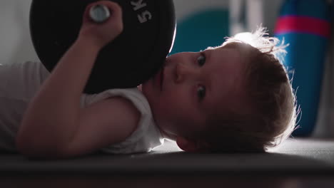 Little-boy-with-heavy-barbell-in-hand-turns-head-to-camera