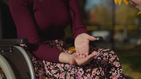Junge-Frau-Sitzt-Im-Rollstuhl-Und-Schaut-Auf-Den-Marienkäfer-Auf-Der-Handfläche