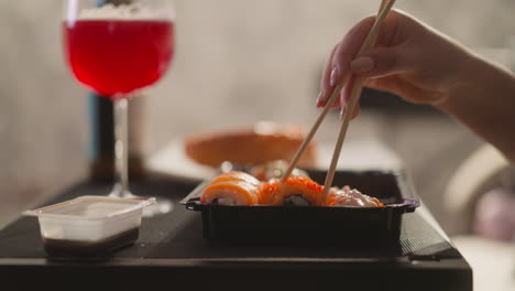 Woman-hand-takes-sushi-roll-with-chopsticks-in-restaurant