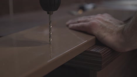 Furniture-maker-drills-holes-with-a-drill-in-the-surface-of-the-table-Close-up