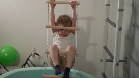 Boy-does-effort-and-pulls-out-legs-of-rope-ladder-in-gym