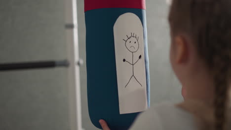 Schoolgirl-draws-upset-man-on-punching-bag-in-playing-room