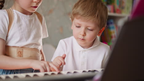 Little-brother-and-sister-press-keys-playing-music-on-piano