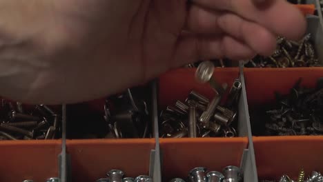 Master-who-produces-and-installs-furniture-pours-many-bolts-into-the-cell-in-the-suitcase-Close-up-Slow-motion