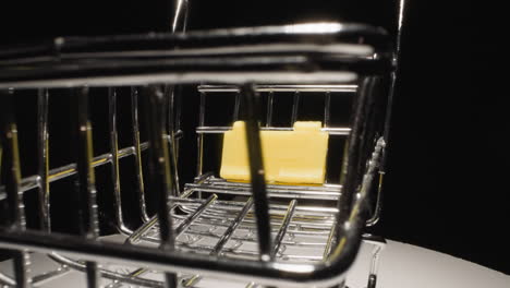 Metal-grid-trolley-with-yellow-stand-on-white-surface-rotates
