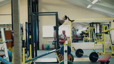 Young-athlete-lgbt-girl-engaged-in-fitness-in-the-gym-pulls-up-on-the-bar