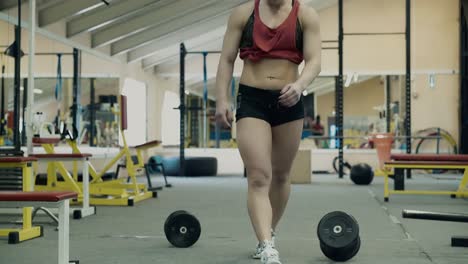 Un-Joven-Atleta-En-El-Gimnasio-Camina-Con-Pesas-Por-El-Pasillo.