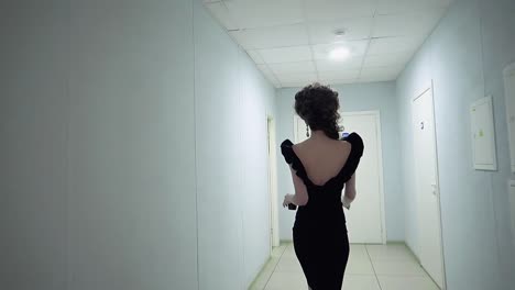 Young-beautiful-girl-in-the-office-in-evening-dress-walking-along-the-corridor-Slow-motion