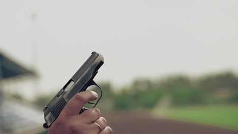 Slow-motion-close-up-starting-pistol-gun-in-hand-makes-shot-to-start-track-and-field-races-at-stadium-by-someone