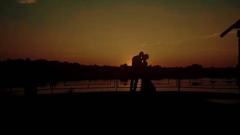 Two-young-people-hugging-against-the-backdrop-of-a-sunset-by-the-river-slow-motion