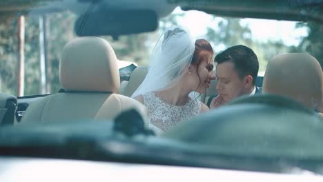 Newlyweds-sitting-car-convertible-look-at-each-other-experience-feelings-of-tenderness