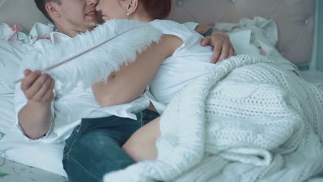 Young-beautiful-couple-resting-in-bed-he-tickles-her-big-feather-1