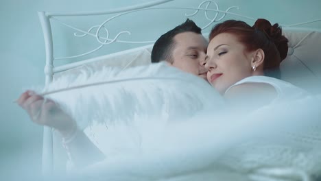 Young-beautiful-couple-resting-in-bed-he-tickles-her-big-feather-2-slow-motion