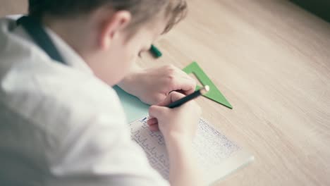 Cu-Junge-Macht-Hausaufgaben-Und-Schreibt-Mit-Einem-Kugelschreiber-In-Ein-Notizbuch-1