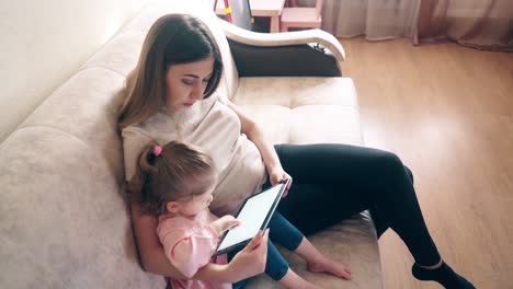 Mutter-Und-Tochter-Sitzen-Auf-Der-Couch-Und-Trainieren-Mit-Einem-Tablet-Computer-1