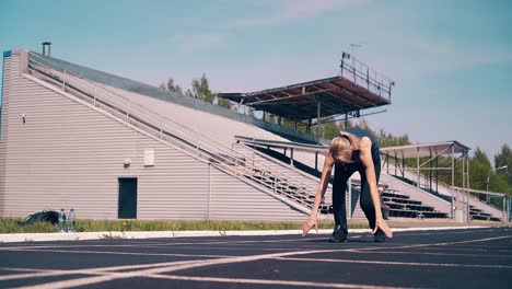 Young-girl-sporty-physique-at-the-stadium-She-goes-to-the-start-line-gets-into-a-low-start