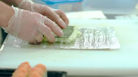 CU-Slow-motion-Cook-is-preparing-a-Japanese-roll-Spreads-on-the-mat-seaweed-nori-with-steamed-rice