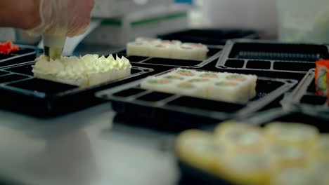 Cook-squeezes-white-sauce-onto-cooked-Japanese-rolls