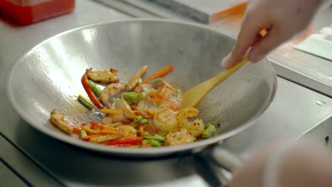 Cook-roasted-shrimps-with-vegetables-in-a-frying-pan-mixed-them-with-a-wooden-spatula