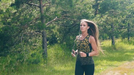 CU-Slow-motion-Young-girl-goes-in-for-sports-in-the-morning-runs-along-pine-forest
