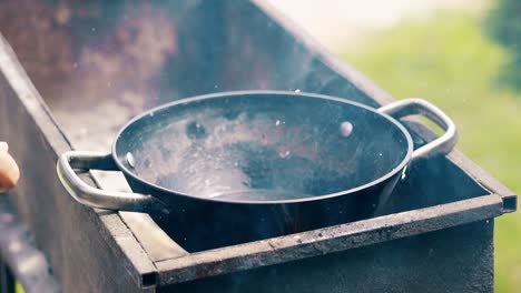 Close-up-Slow-motion-oil-boils-in-cauldron-on-the-coals-on-the-grill